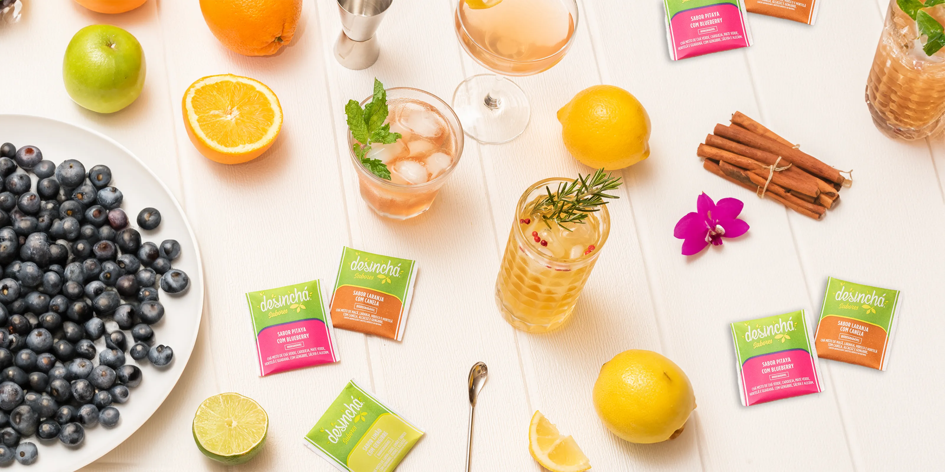 Explore the Flavors of Desinchá: A refreshing tableau of Desinchá tea sachets laid out amidst a spread of fresh fruits and herbal garnishes, representing the natural and diverse flavours of the tea.