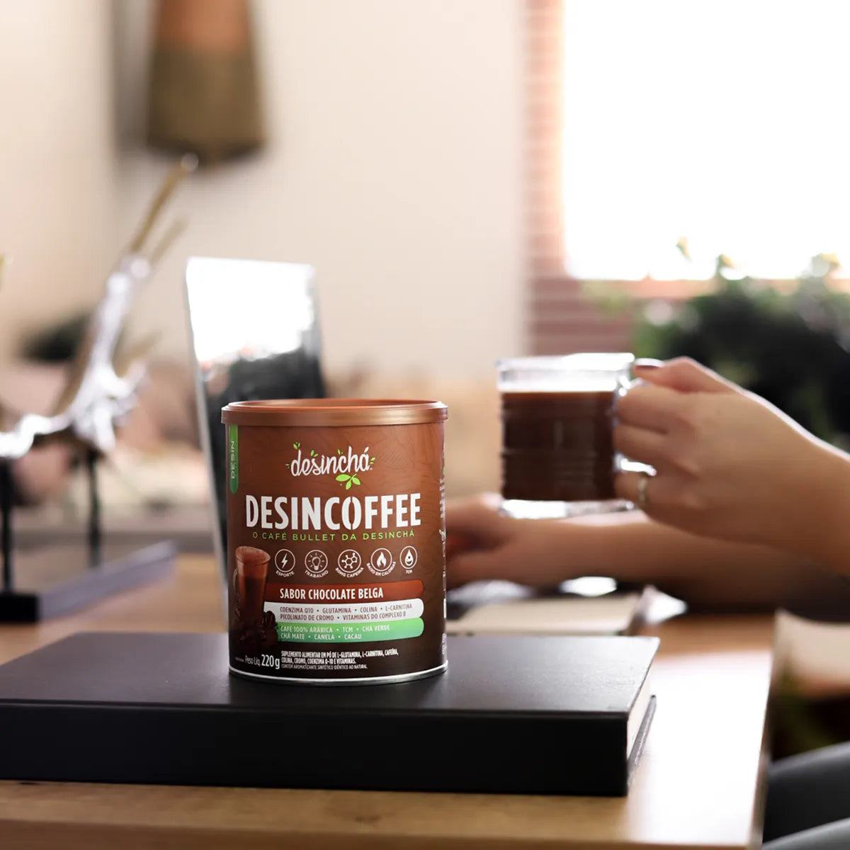 A person enjoying a moment of relaxation with a cup of Belgian chocolate-flavored Desincoffee, with the product prominently displayed on the table, inviting a warm, energizing break.