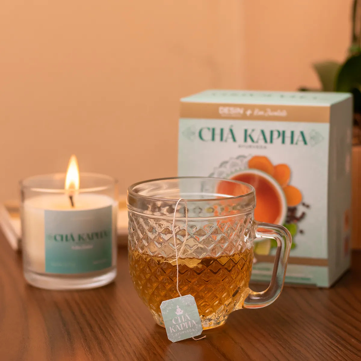 Cozy ambience with a cup of CHÁ KAPHA tea, an Ayurvedic blend for balancing Kapha dosha, accompanied by a soothing candle, against a tranquil background.