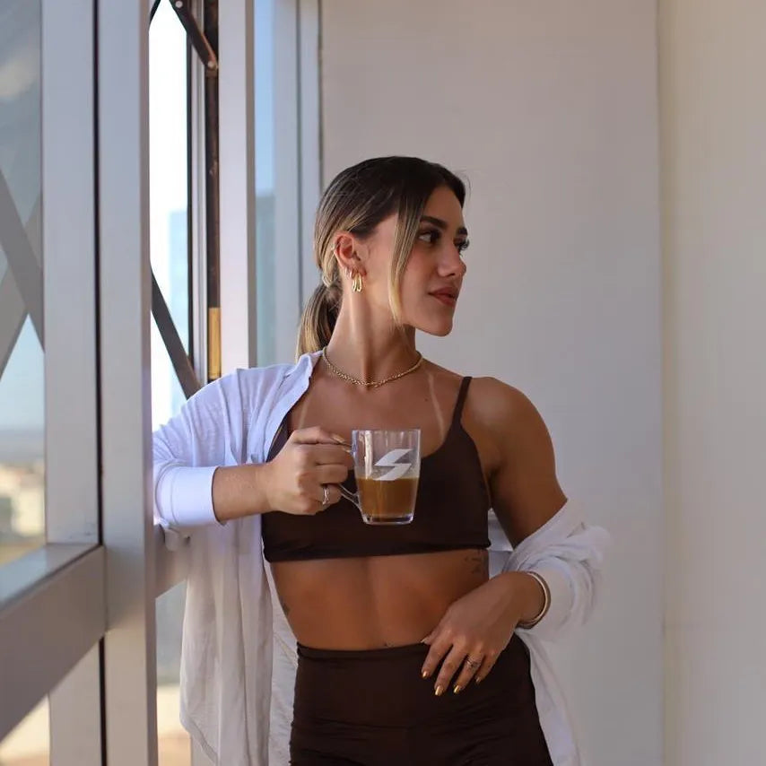 Desincoffee: Woman drinking coffee close to a window before work out