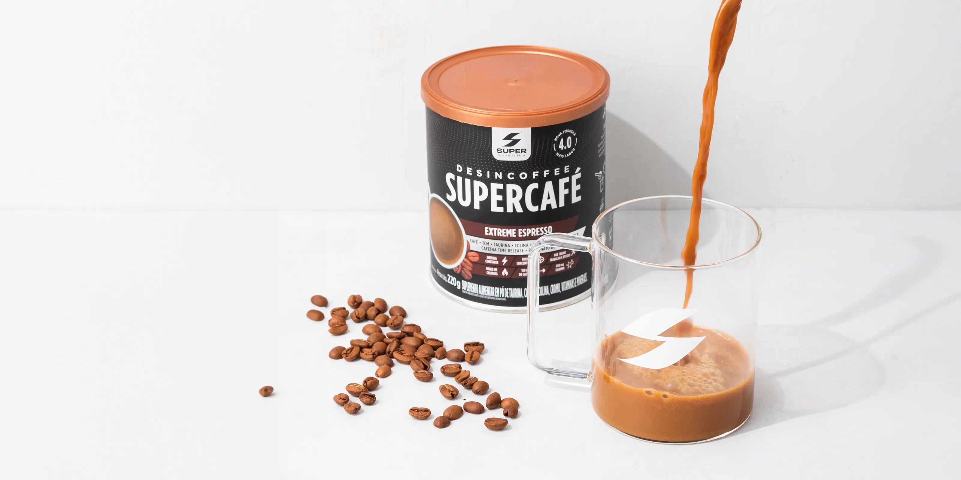 Stream of rich, creamy coffee pouring into a clear glass beside a container of Desincoffee Extreme Espresso and scattered coffee beans, symbolizing a fresh and energetic start.