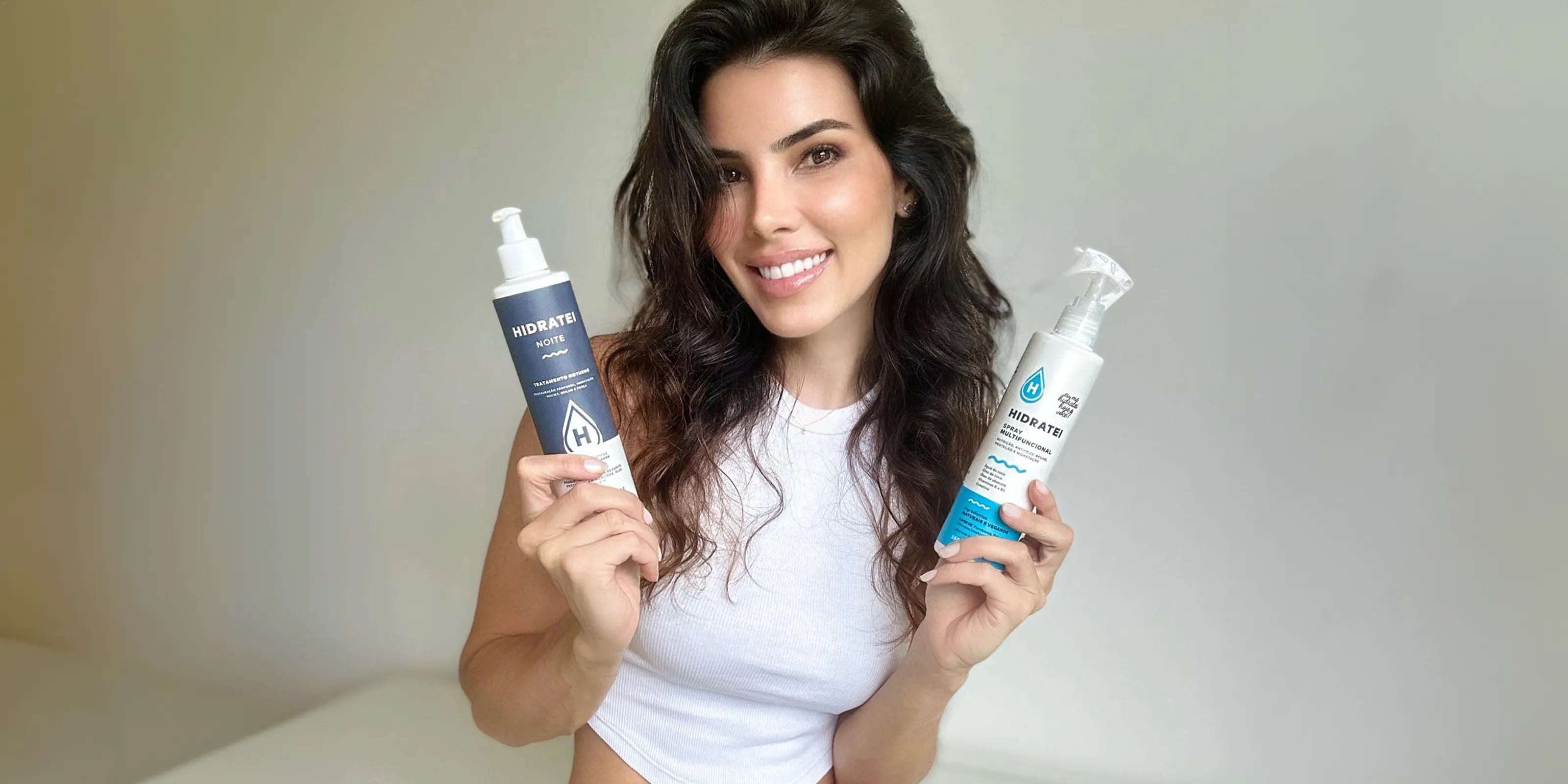 Radiant woman with luscious curls holding Hidratei Night night treatment and Hidratei multifunctional hair care products, showcasing her glowing, healthy hair.