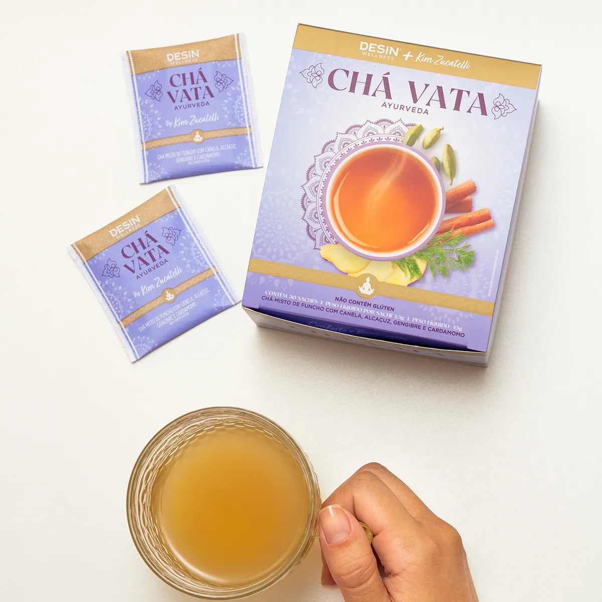 a cup of brewed Chá Vata Ayurveda tea with two tea sachets and the product box visible, highlighting the Ayurvedic blend of cinnamon, licorice, ginger, and cardamom for wellness.